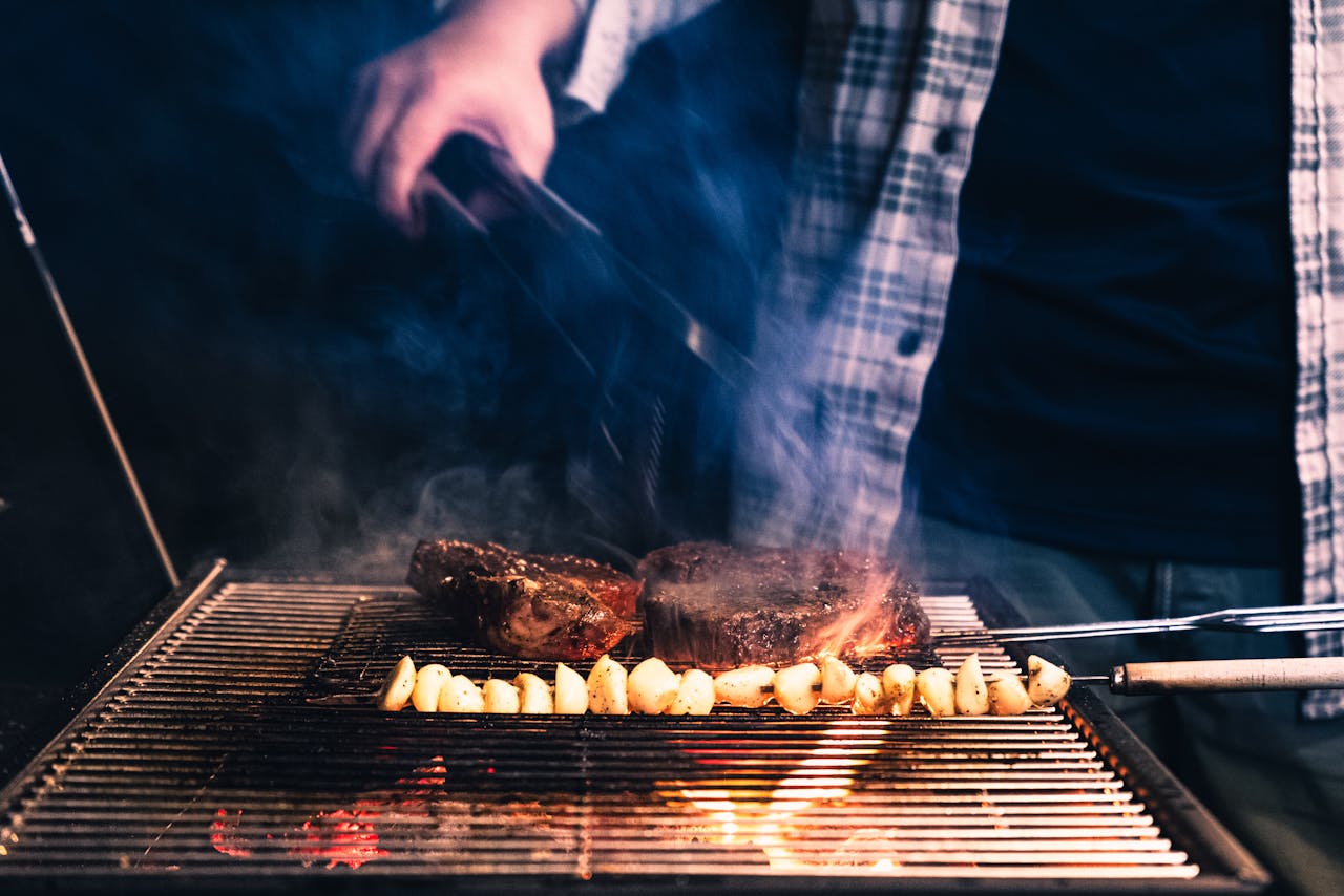 man-grilling-steak-and-vegetables-at-night-32902402